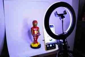 Set de fotografía casero con aro de luz y una figura de Iron Man sobre fondo blanco